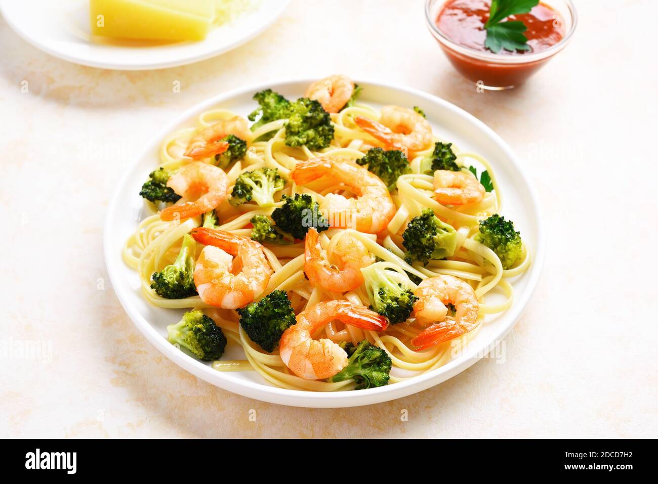 Gamberi e broccoli su piatto su fondo di pietra chiaro. Piatto gustoso per la cena. Foto Stock