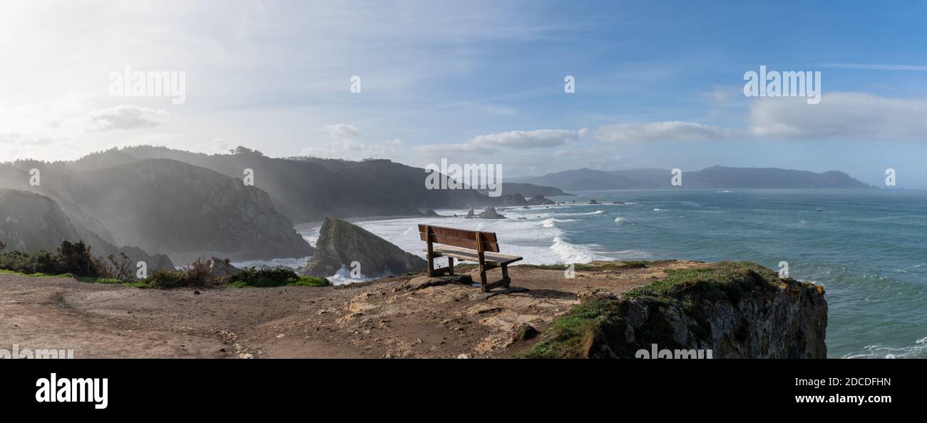 Un panorama di belvedere panoramico con panca in legno su bella costa oceanica con alte scogliere e grandi onde Foto Stock