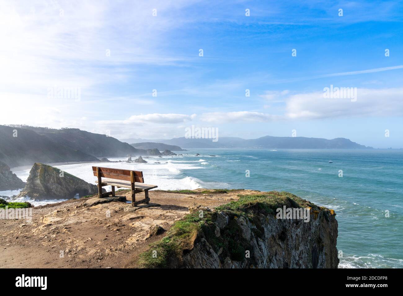 Un punto panoramico con panca in legno sulla splendida costa dell'oceano con alte scogliere e grandi onde Foto Stock