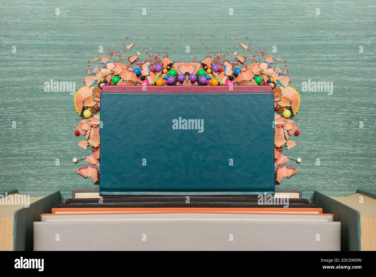 Composizione simmetrica di diversi libri e trucioli colorati a matita e scarti di legno fine su un tavolo. Foto Stock