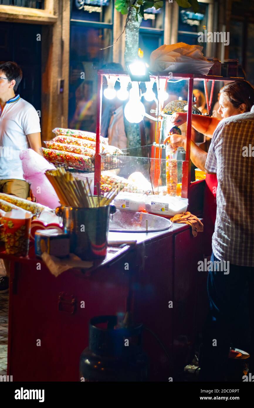 Donne che fanno e riempiono un sacchetto con popcorn a Saint evento popolare giorno Foto Stock