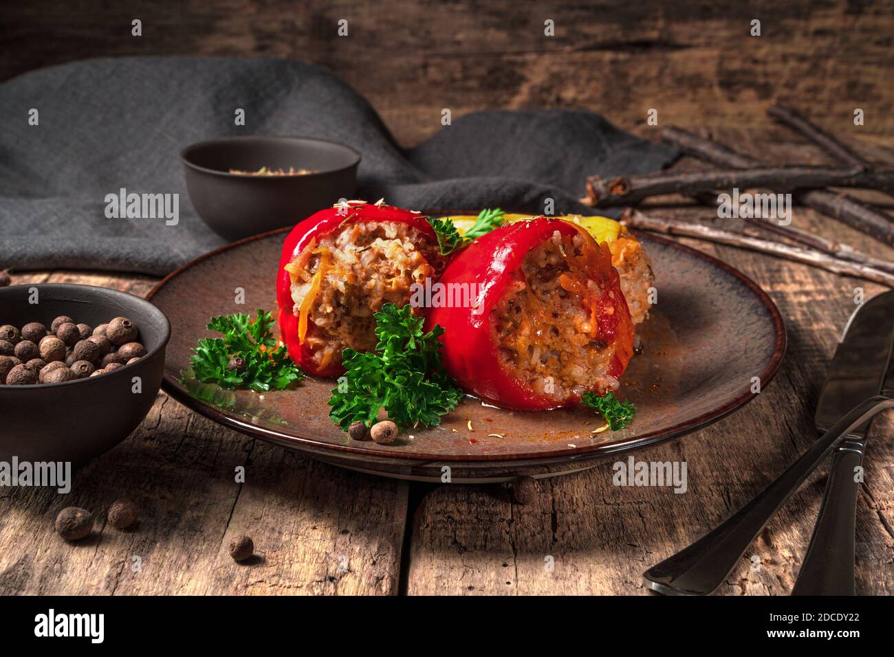 Peperoni ripieni in un piatto su sfondo marrone di legno. Foto Stock