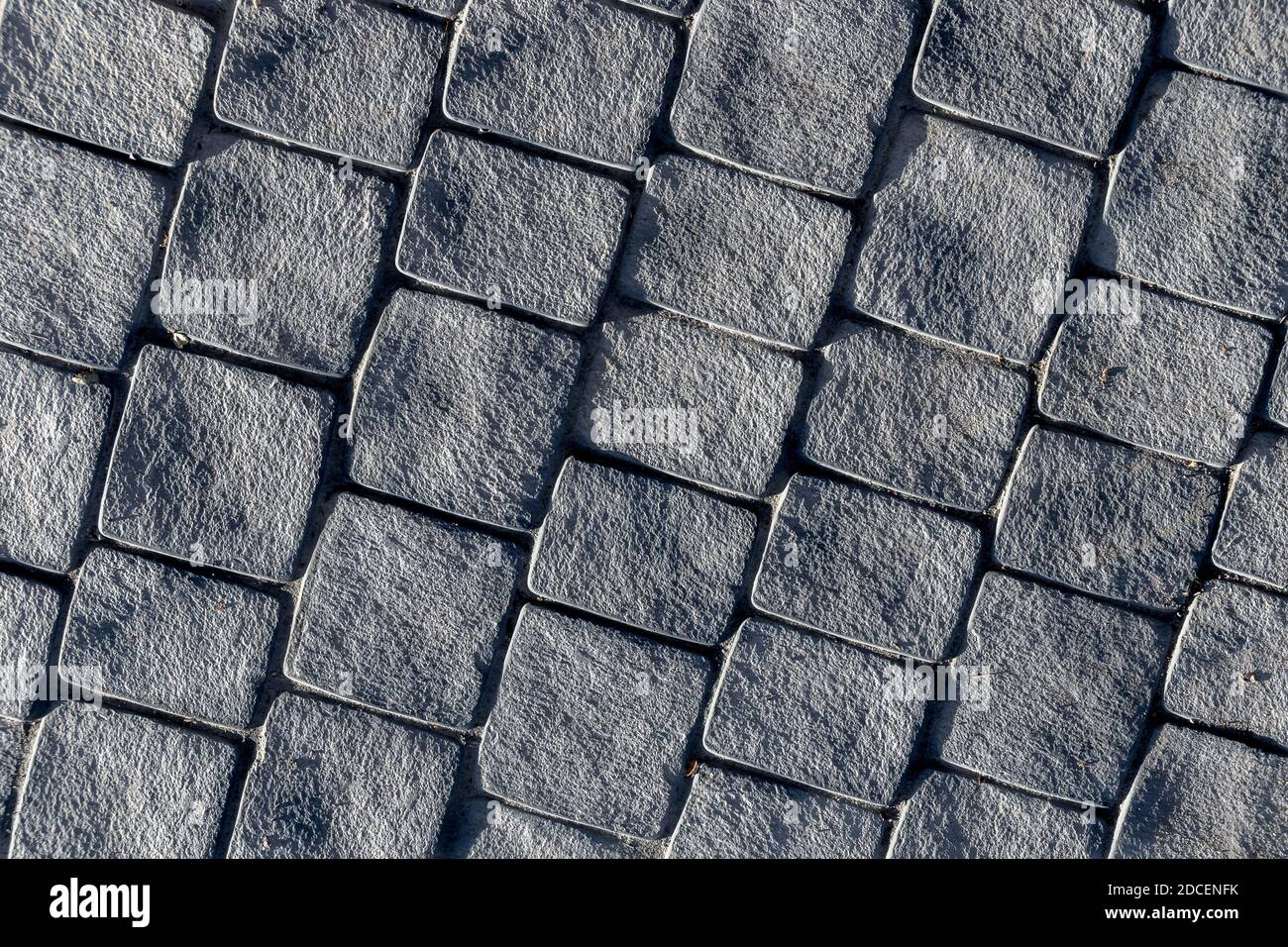 marciapiede lastricato in pietra grigia, direzione diagonale con luce laterale Foto Stock