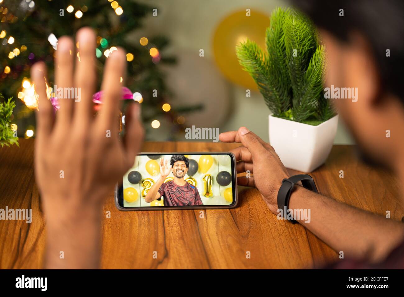Spalla di giovane uomo occupato in videochiamata o chat sul telefono cellulare su 2021 nuovo anno o vigilia di natale - concetto di distanza, celebrata in linea di festa di Natale Foto Stock