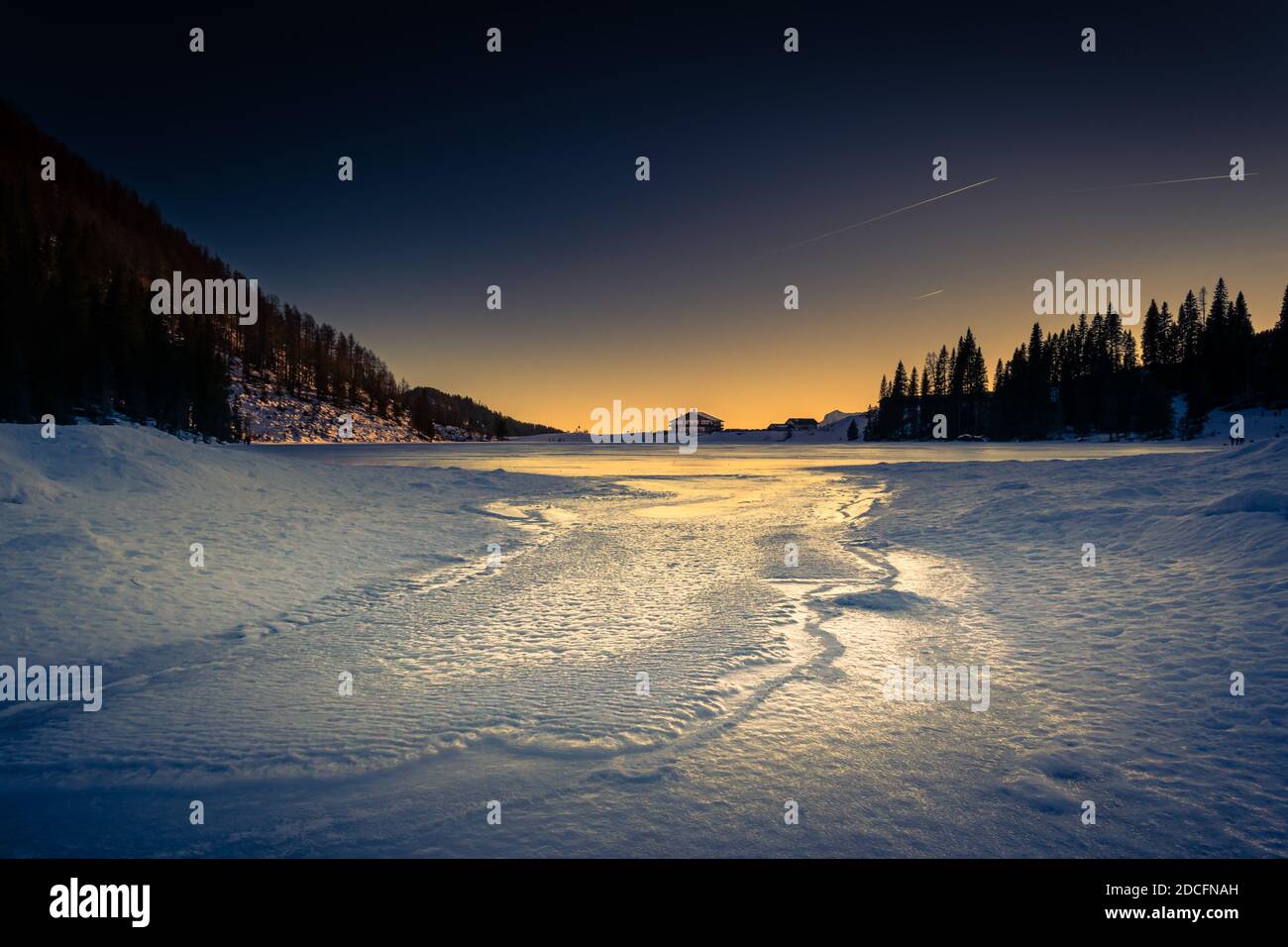 Panorama invernale del Lago Calaita al crepuscolo. Lago ghiacciato, boschi di abeti e prati innevati. Val di Lozen, Trentino-Alto Adige Foto Stock