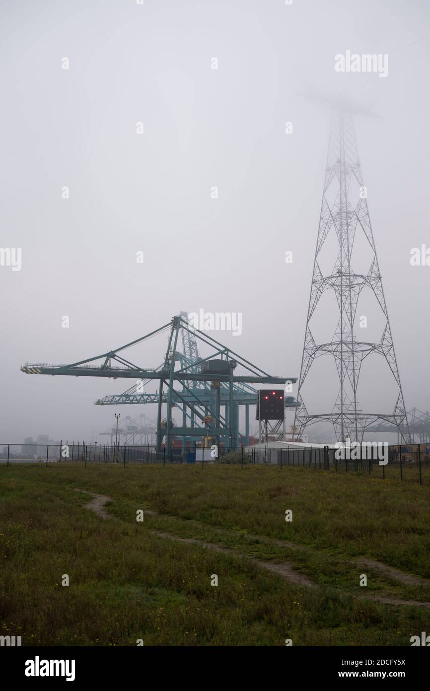 Pilone elettrico in un'area industriale che scompare nel nebbia fitta Foto Stock