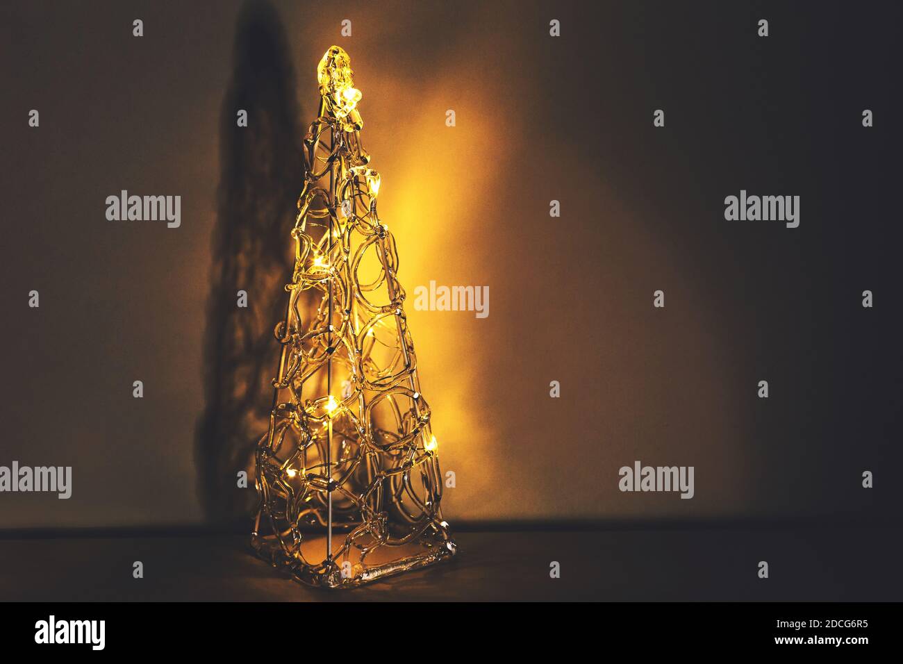Bellissimo albero di natale decorativo brillante in plastica trasparente con illuminazione in caldi colori dorati Foto Stock