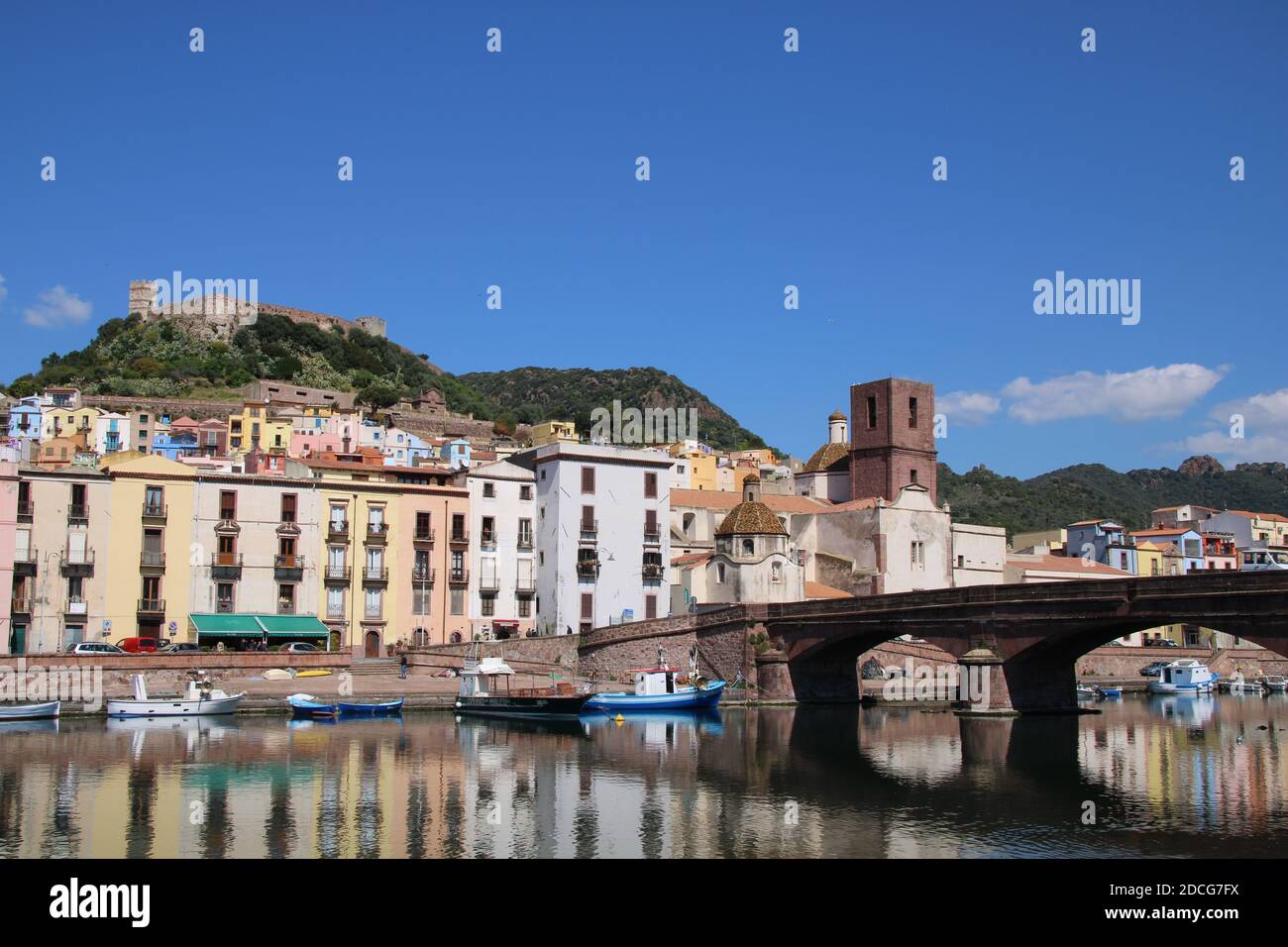 Una giornata di sole a Bosa, Sardegna, Italia lungo il fiume Temo. Case colorate si riflettono sull'acqua, aggiungendo il fascino di questa città storica Foto Stock