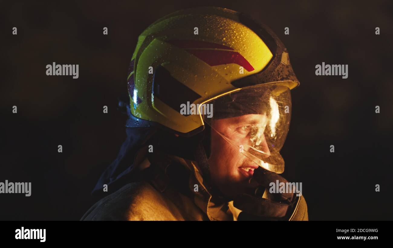 Ritratto del vigile del fuoco in piena uniforme durante la pioggia notturna. Foto Stock