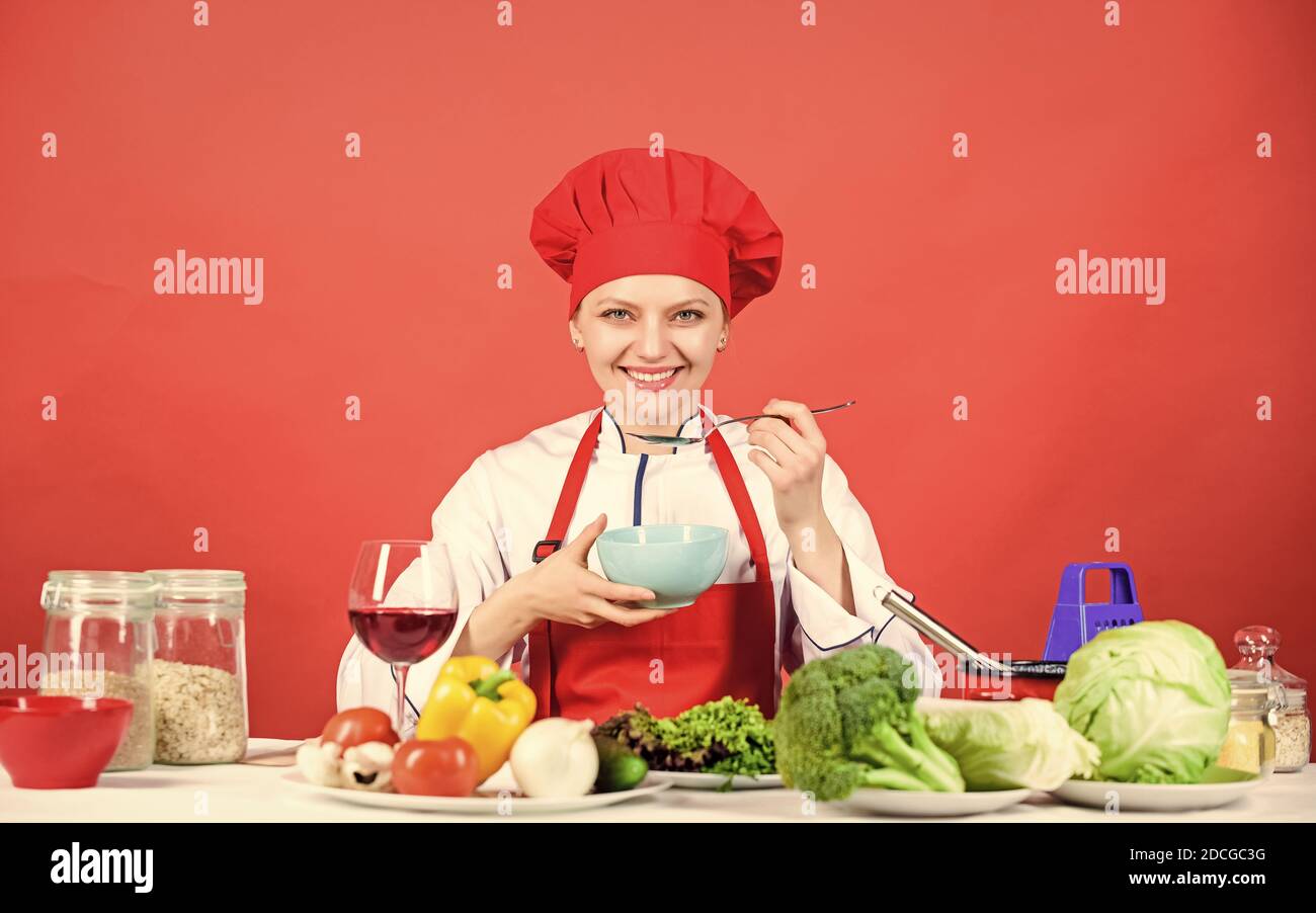 donna in cappello da cuoco. chef professionista su sfondo rosso. donna felice che cucinano cibi sani secondo la ricetta. cibo biologico e vegetariano. Casalinga, menu del ristorante. Dieting. Chi si preoccupa della dieta. Foto Stock