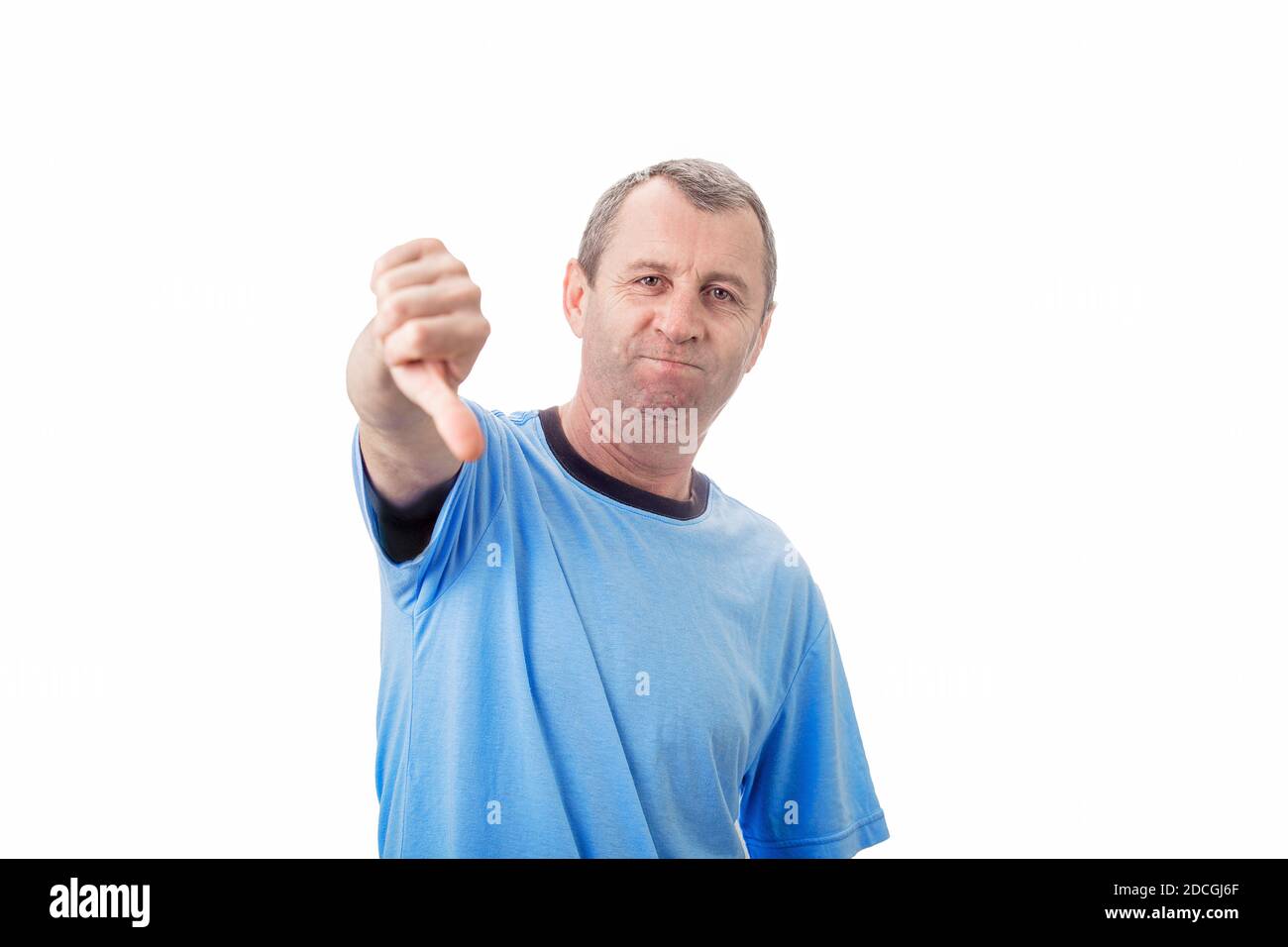 Uomo di mezza età dispiaciuto che mostra i pollici verso il basso, il gesto negativo e il feedback cattivo, guardando la telecamera isolata su sfondo bianco parete. Foto Stock