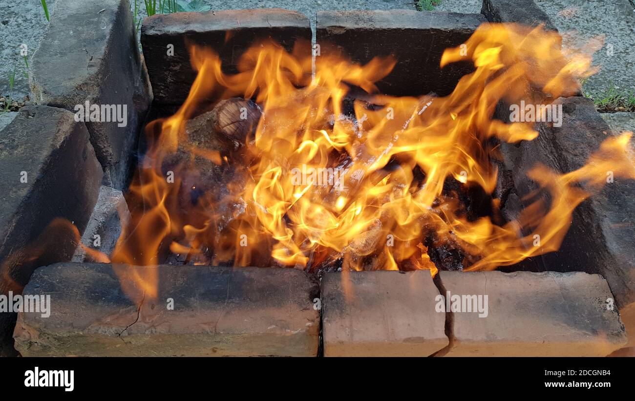 Il fuoco si sta infiammando in tempo ventoso. Closeup di falò di brillamento. Falò da picnic per cucinare il pasto sul fuoco aperto. Concetto di campeggio Foto Stock