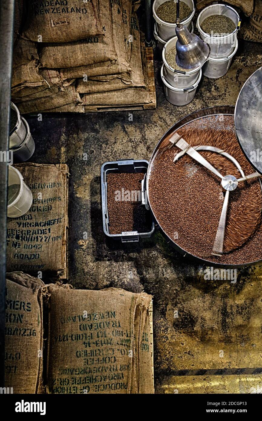 Appena il caffè torrefatto in grani da un grande torrefattore essendo versato nel cilindro di raffreddamento. Motion Blur per i fagioli. Foto Stock