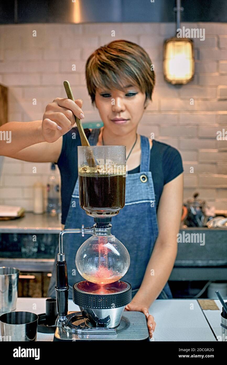 Gran Bretagna / Inghilterra / Londra /Barista femminile che prepara un caffè sifone.Barista che fa caffè sifone Foto Stock