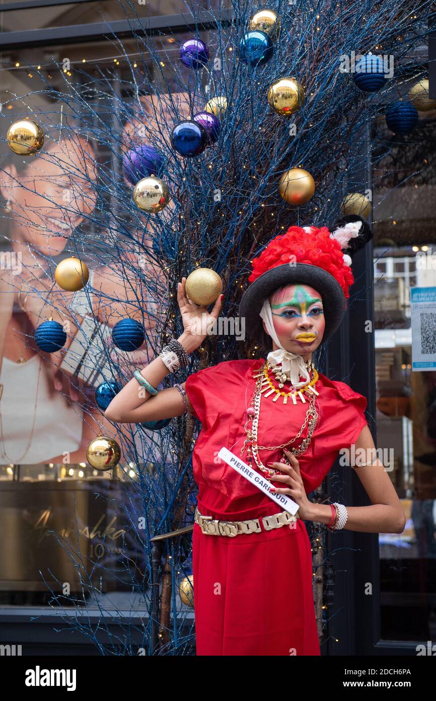 I modelli si levano in piedi fra le decorazioni di Natale mentre mettono in mostra i vestiti dallo stilista Pierre Garroudi, durante una ripresa di moda di flashmob su Oxford Street, Londra. Foto Stock