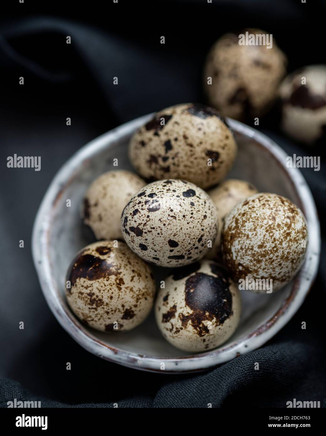 Uova di quaglia in ciotola bianca su sfondo nero, uova di quaglia, mucchio di uova di quaglie in ciotola, uova macchiate, uova macchiate in ciotola, uova di quaglia su sfondo scuro Foto Stock