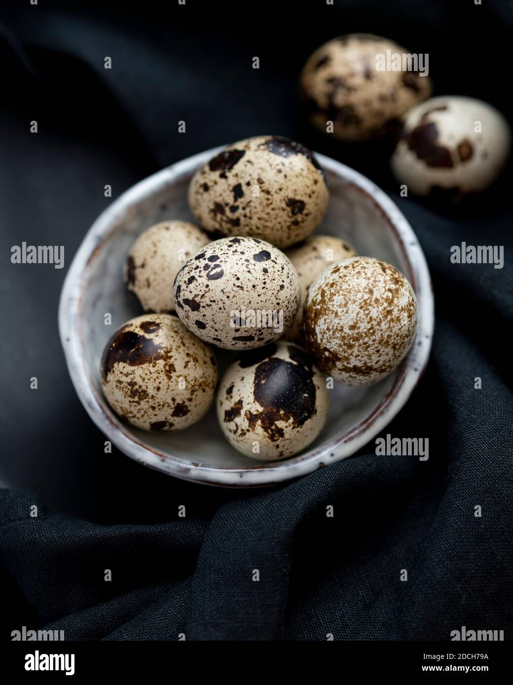 Uova di quaglia in ciotola bianca su sfondo nero, uova di quaglia, mucchio di uova di quaglie in ciotola, uova macchiate, uova macchiate in ciotola, uova di quaglia su sfondo scuro Foto Stock