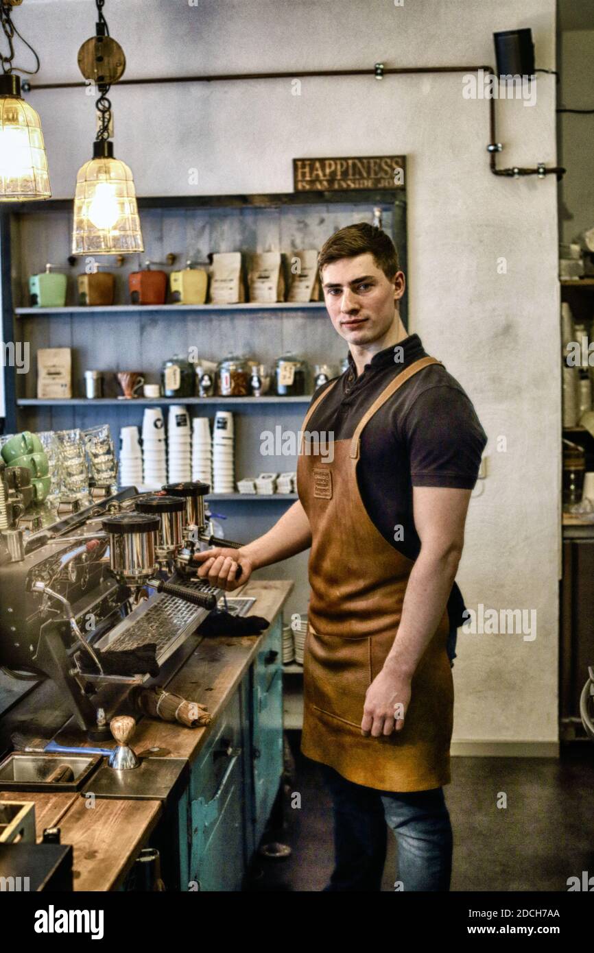 Giovane barista maschile che prepara caffè con macchina espresso. Foto Stock