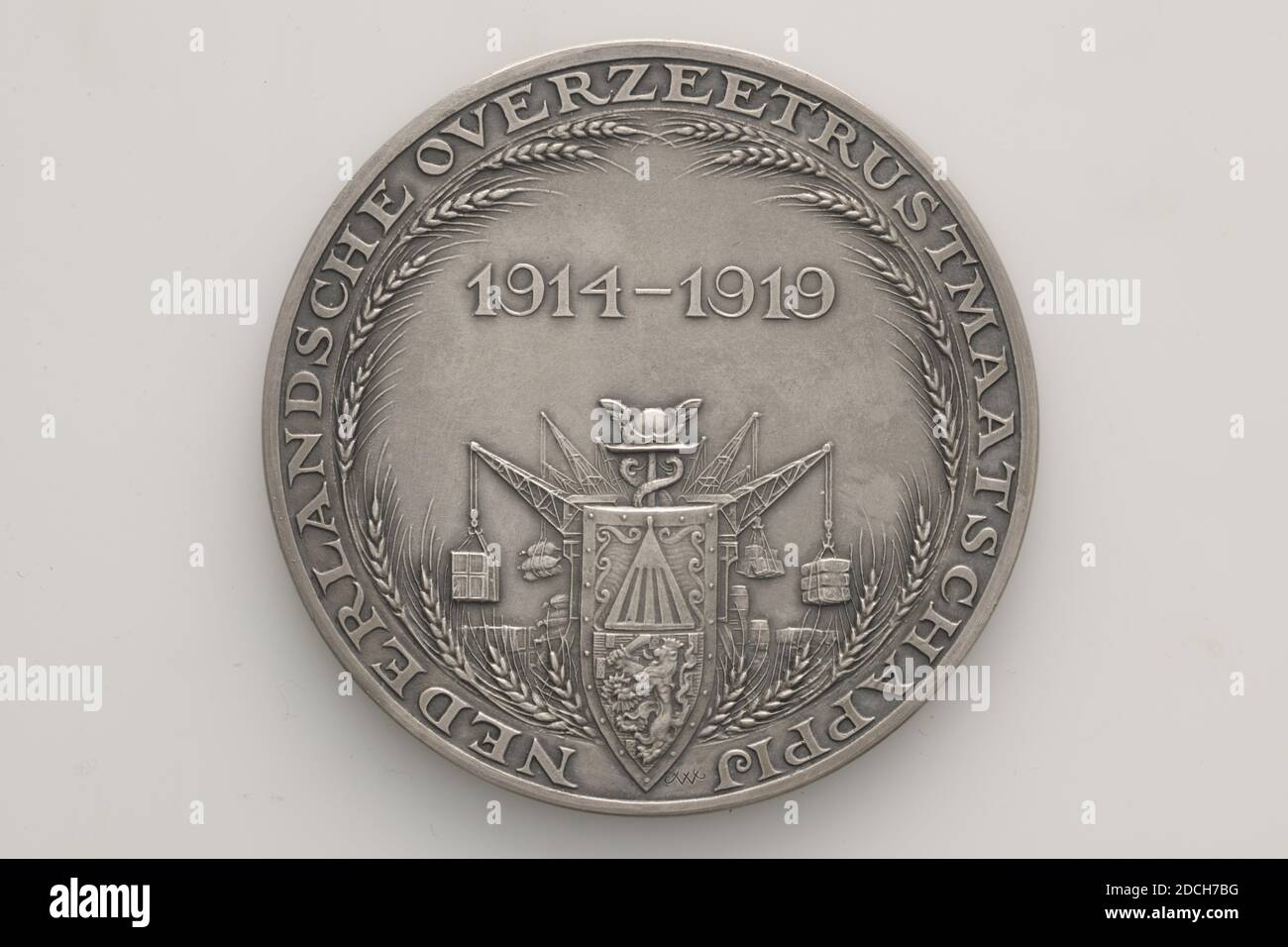 Medaglia commemorativa, Johannes Cornelis Wienecke, 1919, Generale: 6.5 x 0.3cm 65 x 3mm, peso: 99.5g, drago, piroscafo, segno di arma, armi e munizioni, medaglia commemorativa d'argento, coniata per la Nederlandsche Overzee Trustmaatschappij, 1919. Sull'ossale è lo stemma con lo scudo olandese con il leone di arrampicata circondato da emblemi del commercio e dell'industria. Sopra di essa si trova l'iscrizione 1914-1919. Tutto questo è circondato da spighe di mais e circondato dalla circolare NEDERLANDSCHE OVERSEETRUSTMAATSCHAPPIJ. Nella parte inferiore della circolare è inciso JWC. Al contrario, è presente un Foto Stock