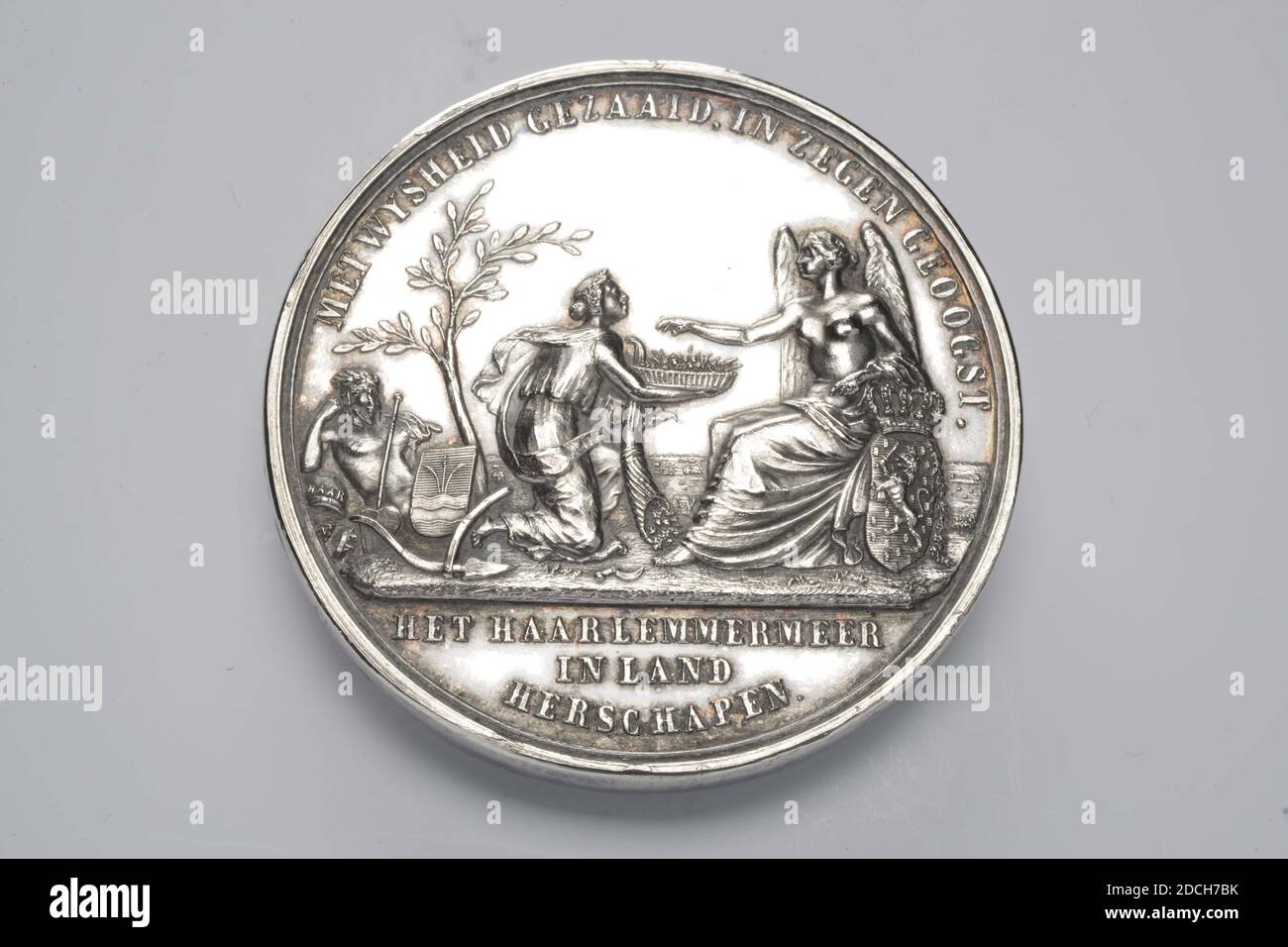 Medaglia commemorativa, Moses de Vries jr, 1853, coniato, Generale: 5.1 x 0.4cm 51 x 4mm, peso: 76,7g, frutta, femmina, corno d'abbondanza, coppa, segno d'arma, uomo, albero, medaglia commemorativa d'argento, colpito sulla bonifica del Haarlemmermeer, 1853. Sull'ossetto è una figura femminile inginocchiata che indossa un corno rovesciato di abbondanza nella mano sinistra. La figura femminile offre una seduta, alata donna la vergine olandese? un cestino di frutta. Accanto alla donna seduta, lo stemma dell'Olanda può essere visto uno scudo coronato con il leone di arrampicata in esso. Nell'angolo sinistro della scena è possibile vedere un albero con Foto Stock