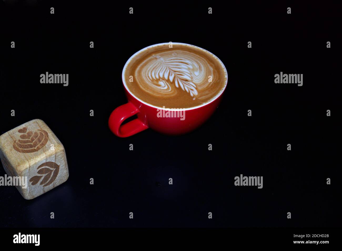 Latte art dice e caffè con latte art in tazza rossa e sfondo nero. Foto Stock