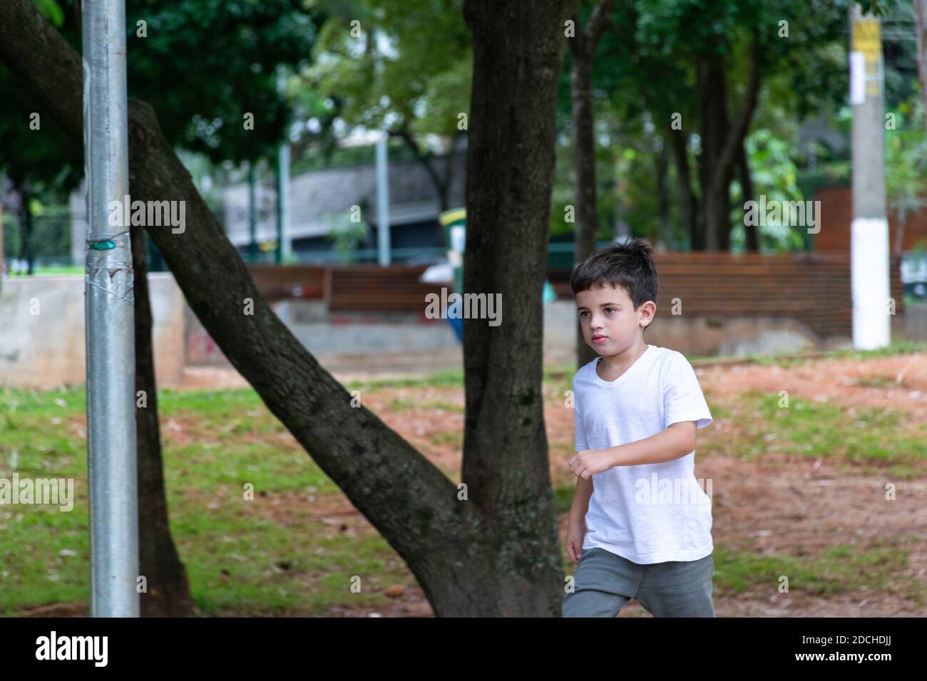 Bambino di 6 anni che cavalca uno scooter e salta un tronco nella bella piazza Horácio Sabino. Foto Stock