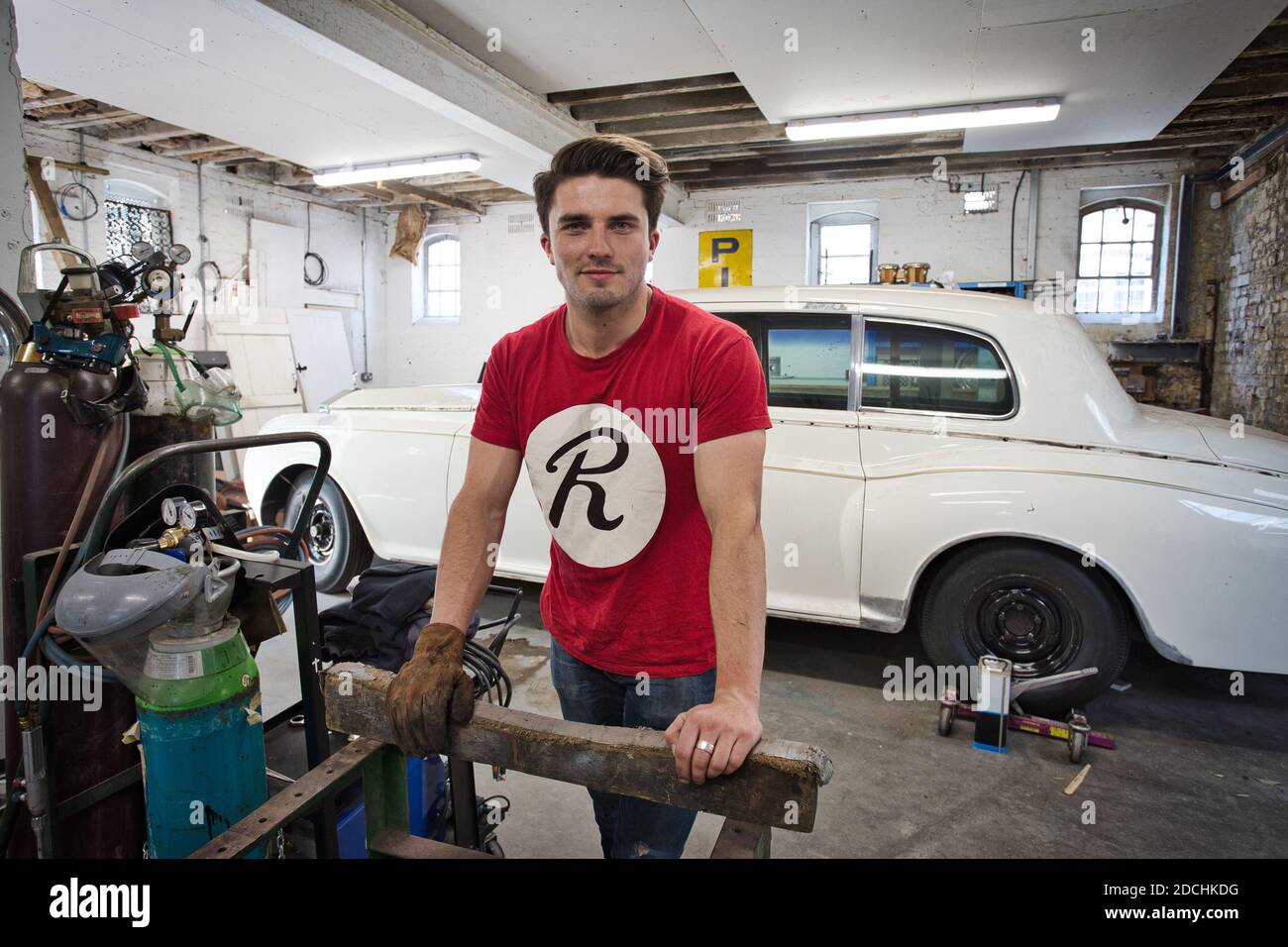 Buon meccanico di automobile osservante che lavora in garage sulla riparazione di vecchio timer Foto Stock