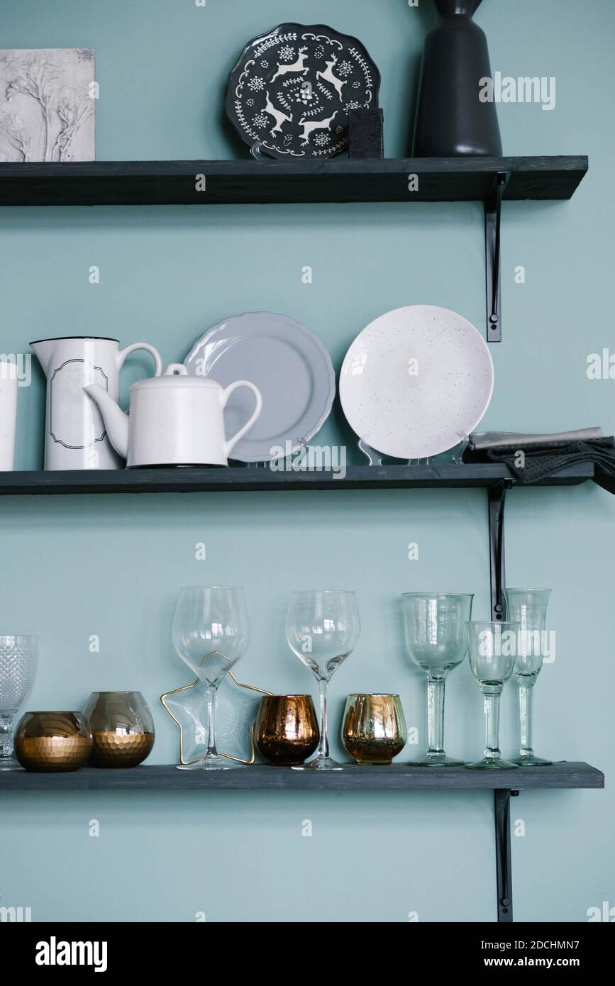 Utensili da cucina sugli scaffali: Bicchieri di vetro, bicchieri d'oro, piatti, teiere in cucina Foto Stock