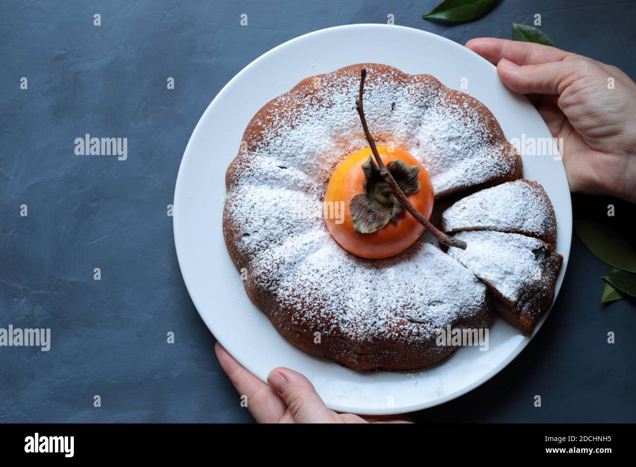 Torta di persimmon al cioccolato fatta in casa con zucchero in polvere isolato su sfondo grigio. Vista dall'alto. Foto Stock
