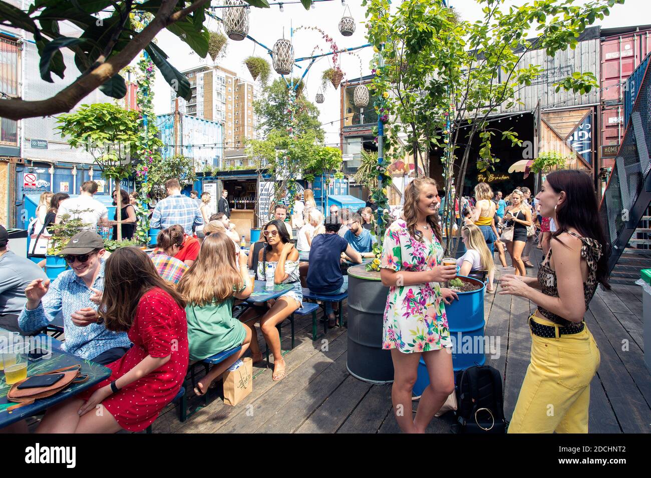 Le persone godono di un drink a Brixton pop, pop up contenitore bar e ristoranti a Brixton, London, Regno Unito Foto Stock