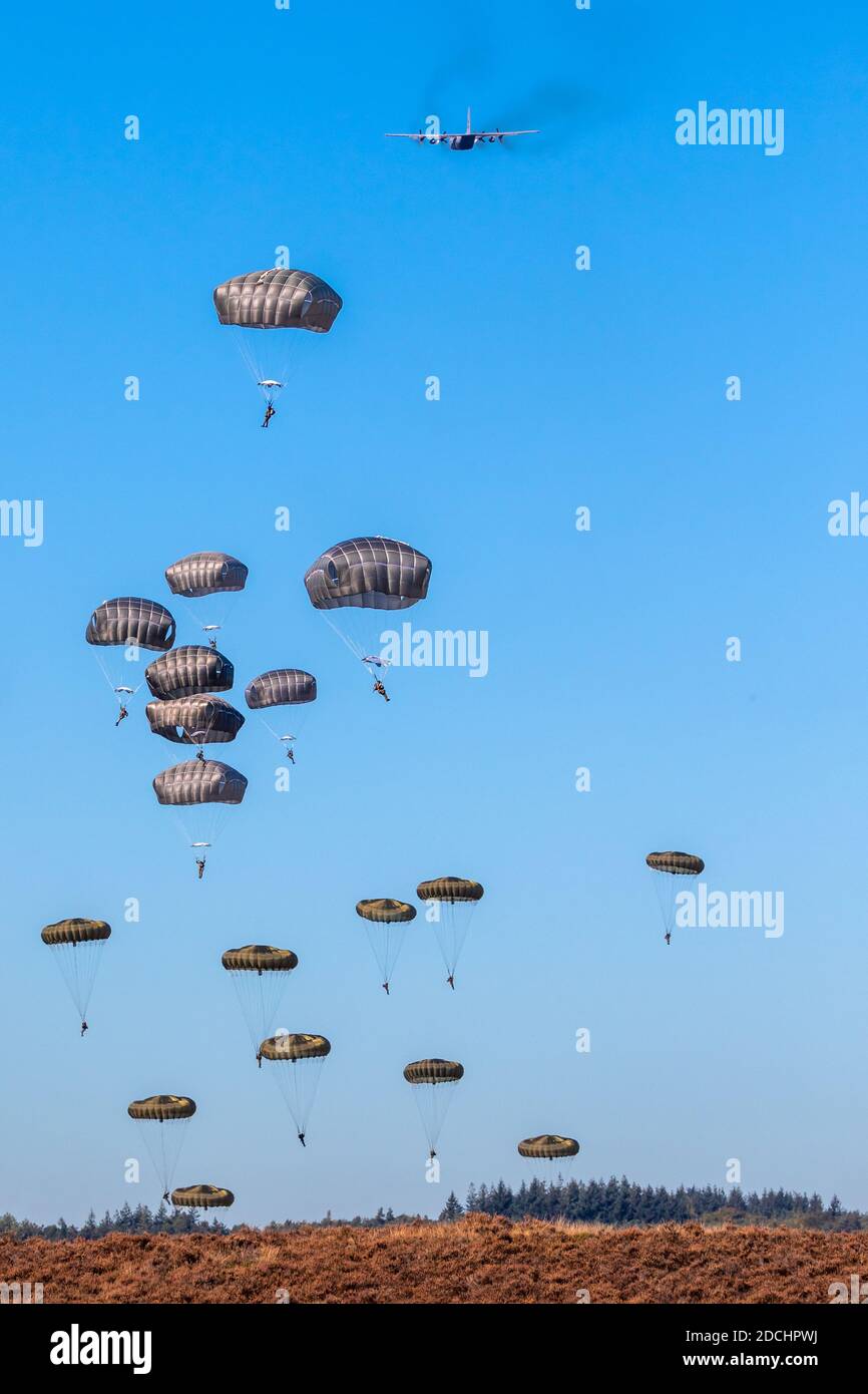 Paracadutisti militari paracadutisti paracadutisti che saltano fuori da un aereo di forze aeree in una giornata di cielo blu chiaro. Foto Stock