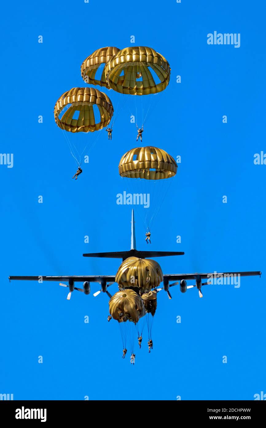Paracadutisti militari paracadutisti paracadutisti che saltano fuori da un aereo di forze aeree in una giornata di cielo blu chiaro. Foto Stock