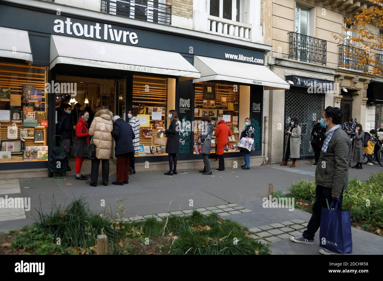 Le persone si accodano al servizio 'Click and Collect' della libreria  'Atout Livre' a Parigi, in quanto tutti i negozi non essenziali sono chiusi  in Francia per combattere l'epidemia di coronavirus (COVID-19),