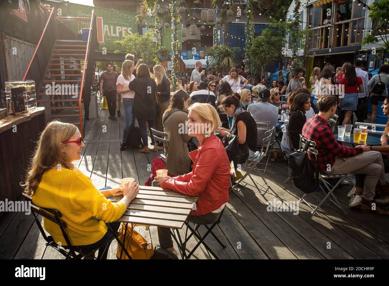 Le persone godono di un drink a Brixton pop, pop up contenitore bar e ristoranti a Brixton, London, Regno Unito Foto Stock