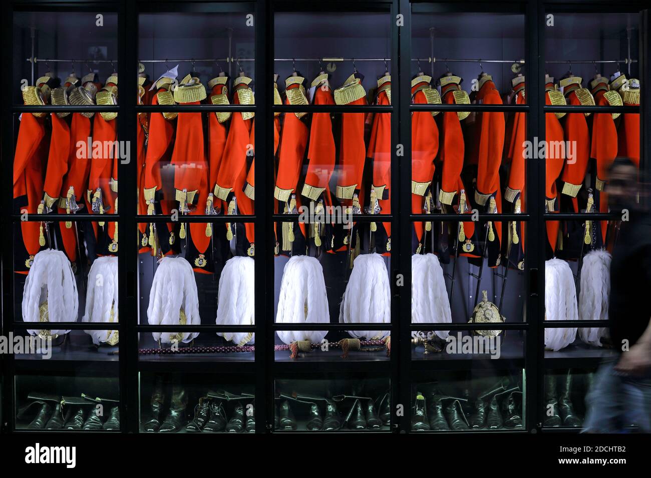 Armadietto Gives & Hawkes contenente una fila di uniformi scarlatto, abbellite con nappine d'oro e aiguillette intrecciate. Foto Stock