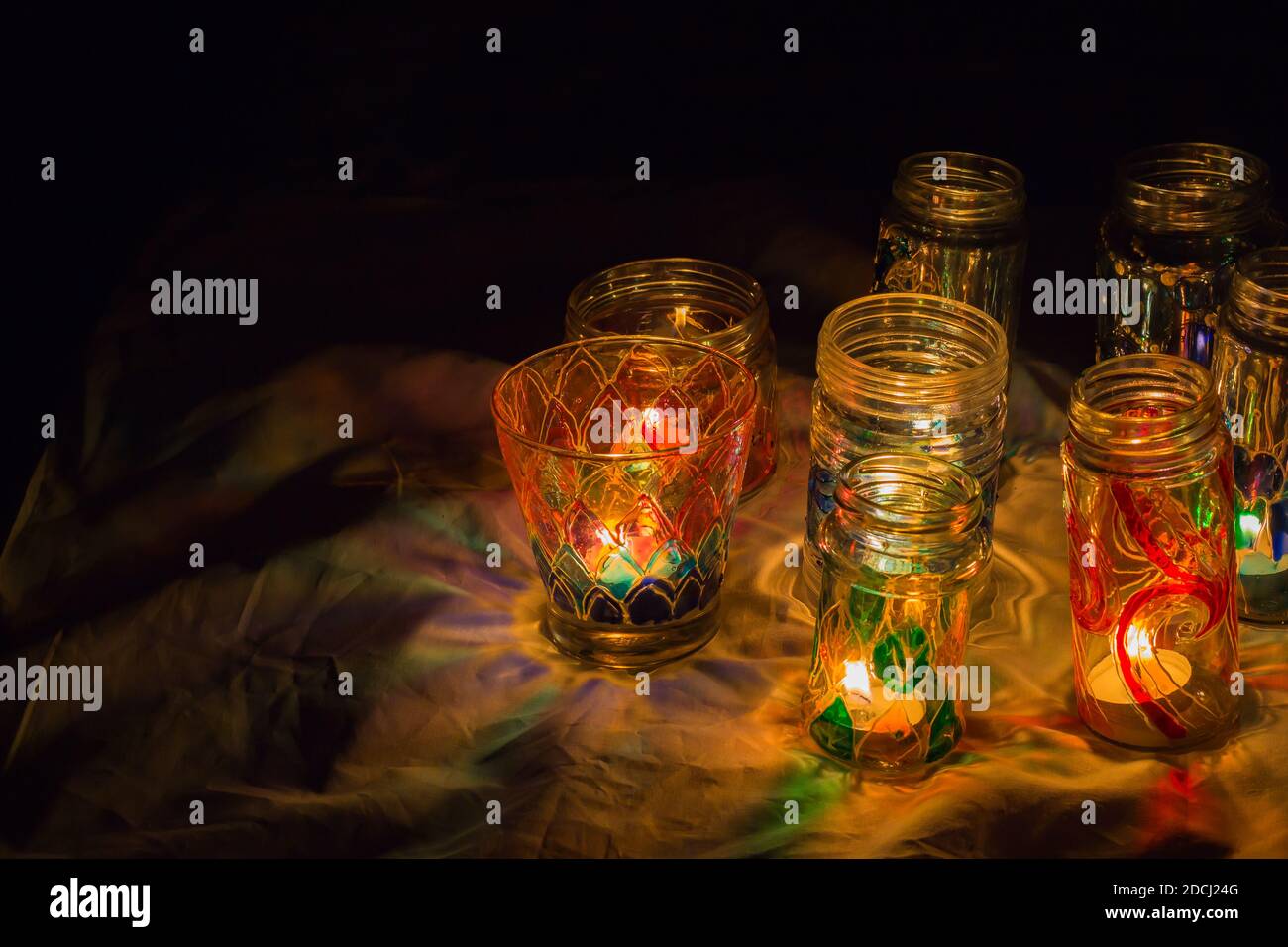 belle bottiglie e tazze di vetro colorate dipinte a mano illuminate con  candele di natale con fiamma incandescente durante la festa. copia spazio b  Foto stock - Alamy