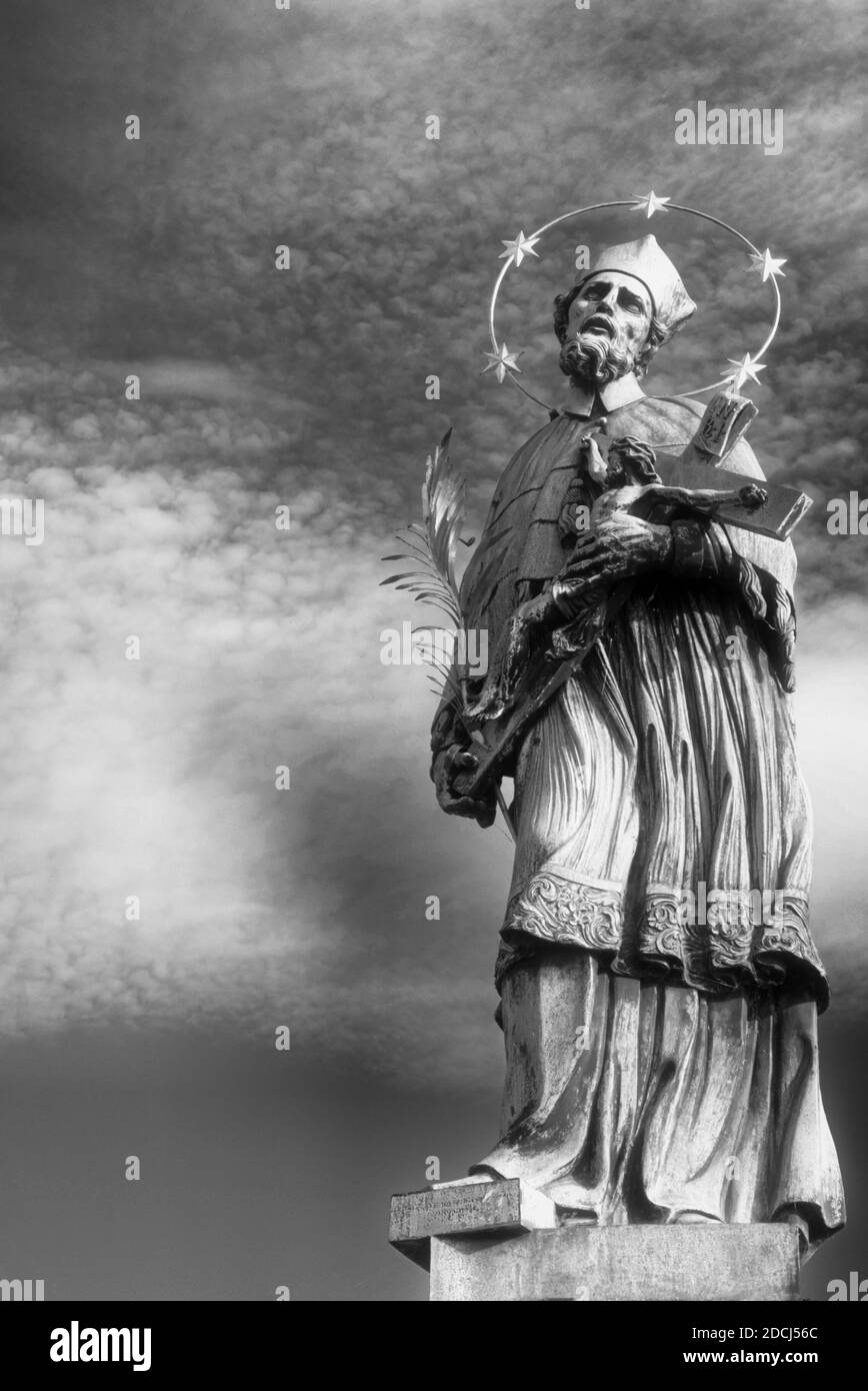 Statua di Giovanni di Nepomuk sul Ponte Carlo a Praga contro il cielo. Monocromatico. Foto Stock