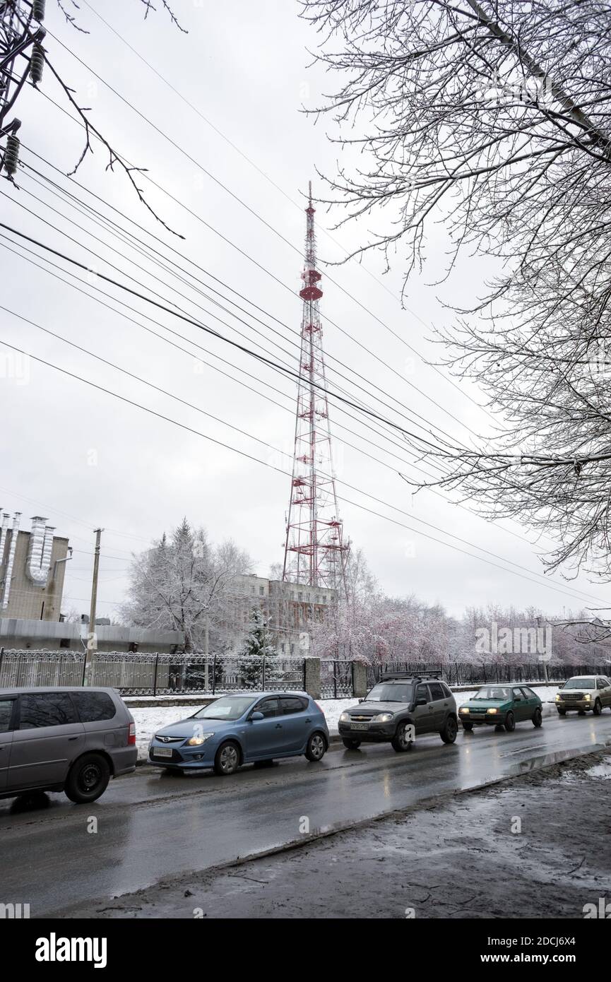 Le auto si guidano in fila su una strada sporca sullo sfondo di una torre televisiva nella città di Novosibirsk. Russia. Foto Stock