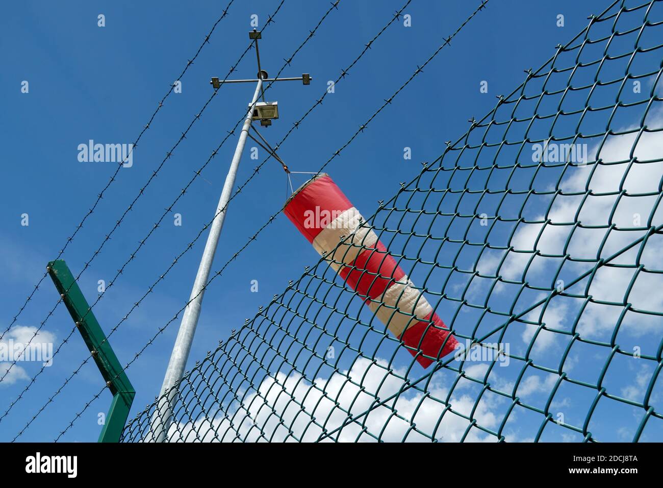 L'indicatore di direzione del vento facilita l'identificazione visiva della direzione e della velocità del vento negli aeroporti e negli eliporti. Vista ad angolo basso sulla recinzione. Foto Stock