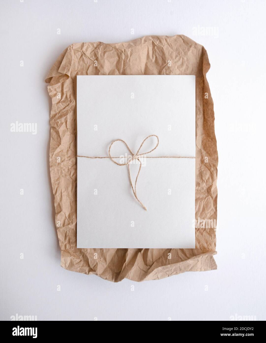 Foglio bianco giacente su carta artigianale sgualcita. Piatto Foto Stock