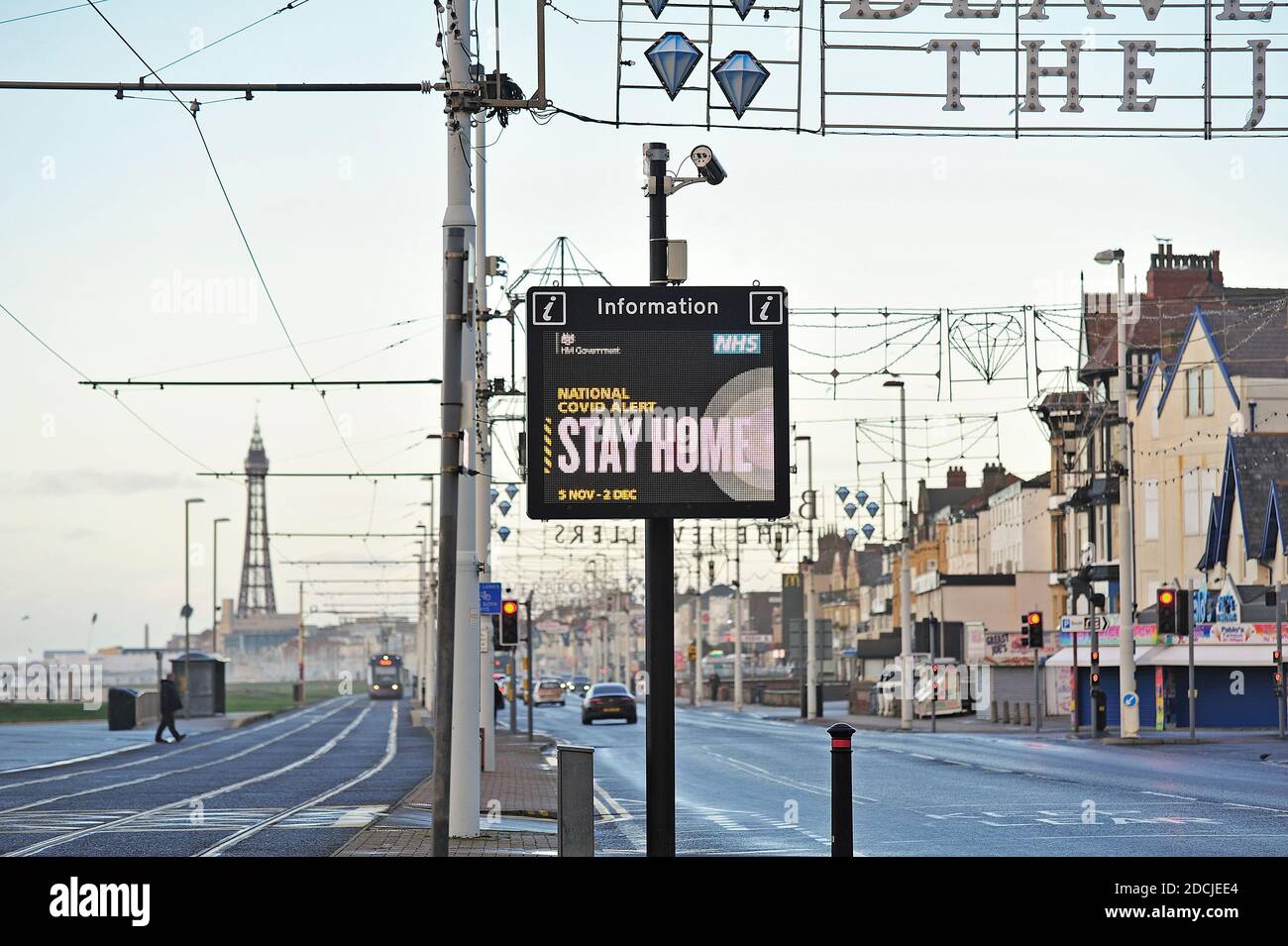 Pochi utenti della strada che passano National Covid Alert segnale elettronico Tra la strada principale e la pista del tram sul lungomare di Blackpool Foto Stock