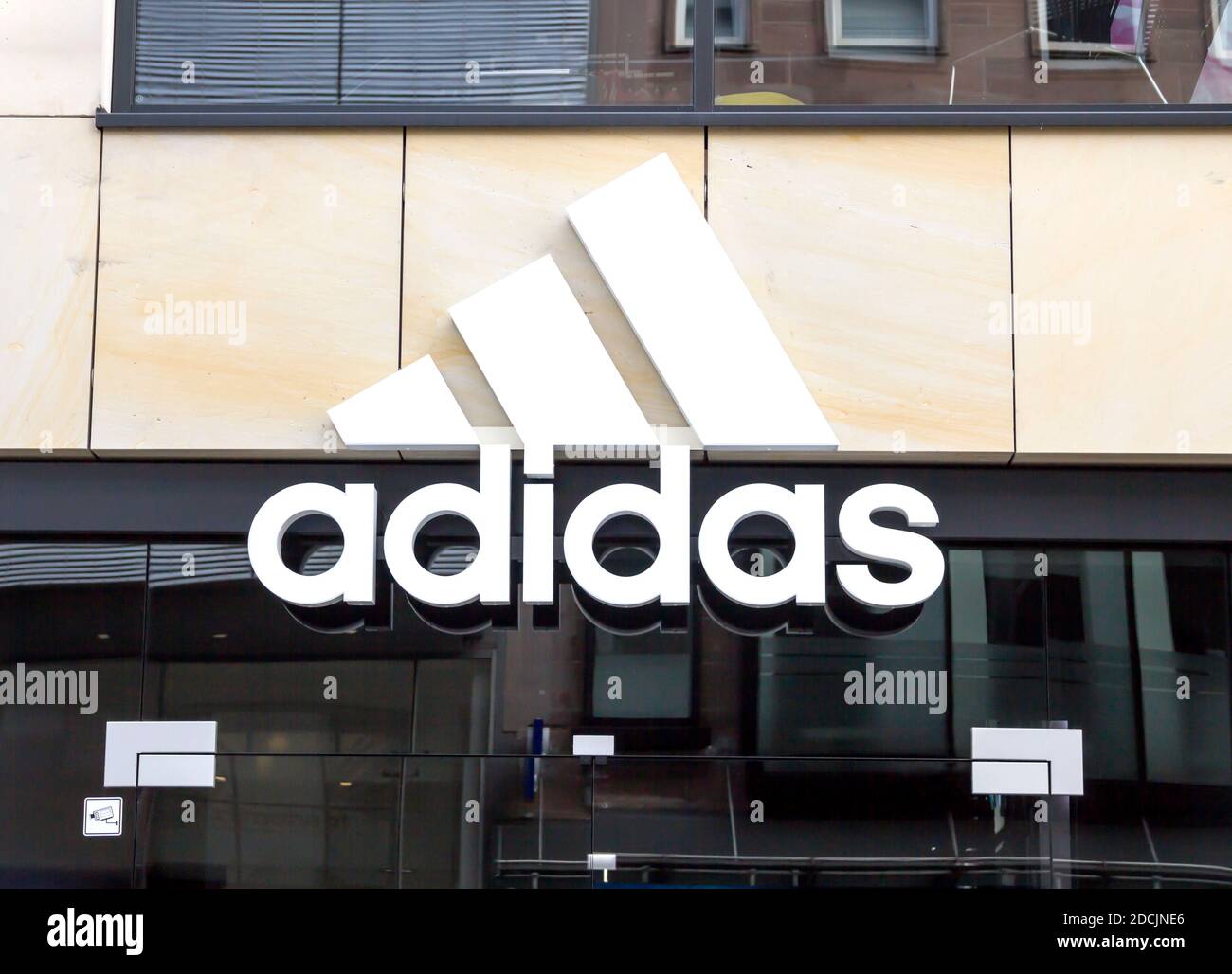 Logo Adidas su una parete. Adidas è una multinazionale tedesca che produce  scarpe sportive, abbigliamento Foto stock - Alamy