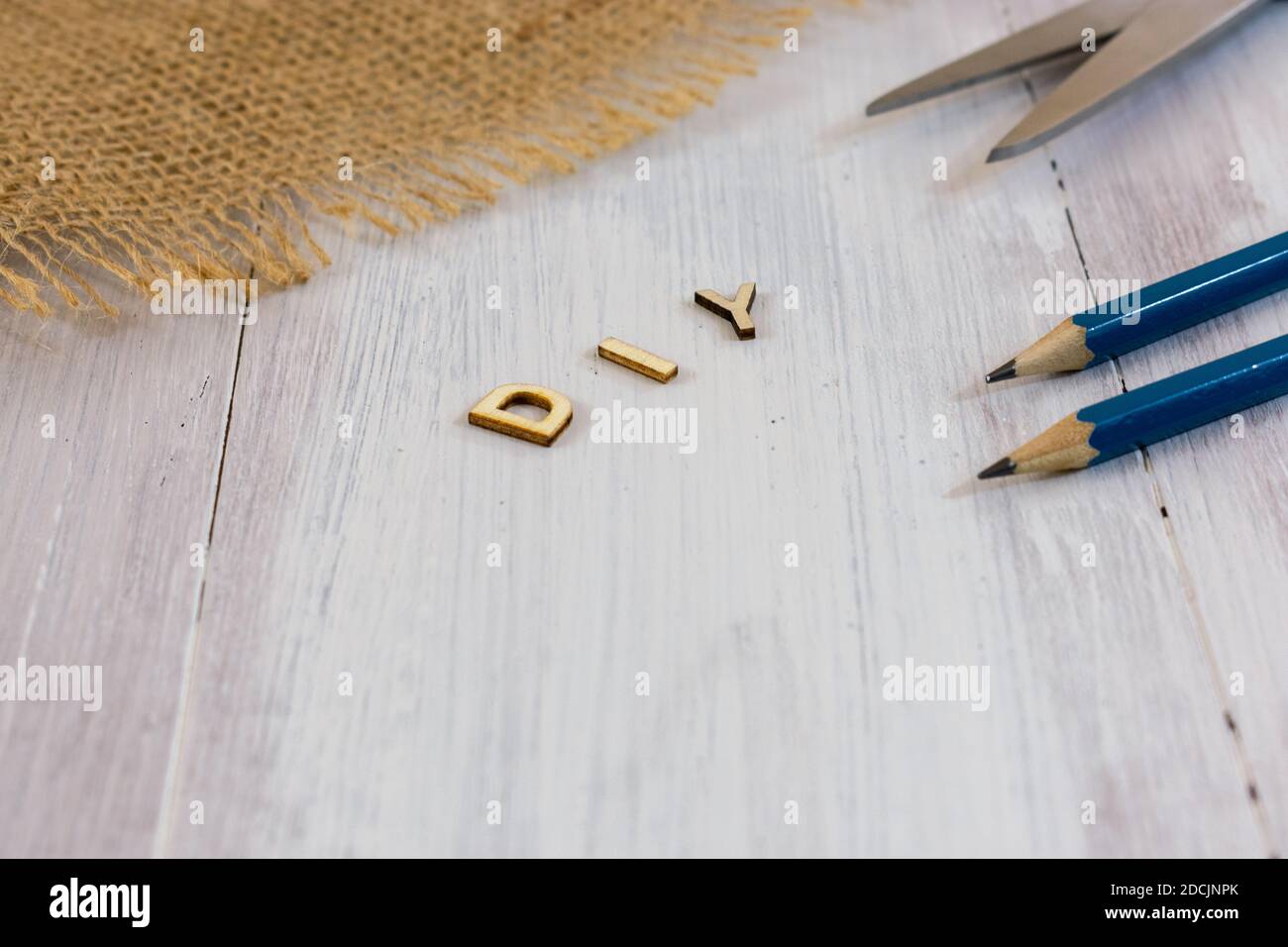 Lettere di legno di DIY, fallo voi stessi con matite, forbici e burlap su sfondo di legno con spazio di copia Foto Stock