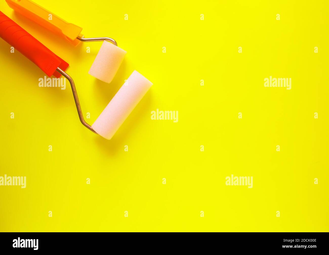 Strumenti di riparazione a casa su sfondo giallo brillante. Due rulli in schiuma per la colorazione delle pareti da vicino. Foto Stock