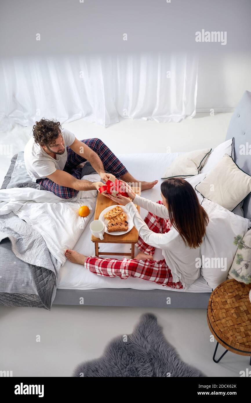 vista dall'alto di una donna che riceve un regalo da un uomo mentre fa colazione a letto. immagine verticale, spazio di copia Foto Stock