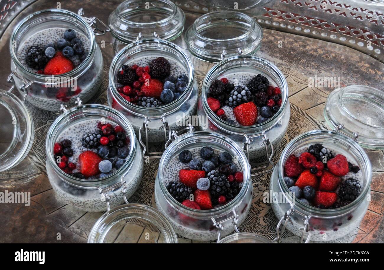 Sei ciotole di vetro di semi di chia pudding con frutta mista bacche su fondo vassoio argento Foto Stock