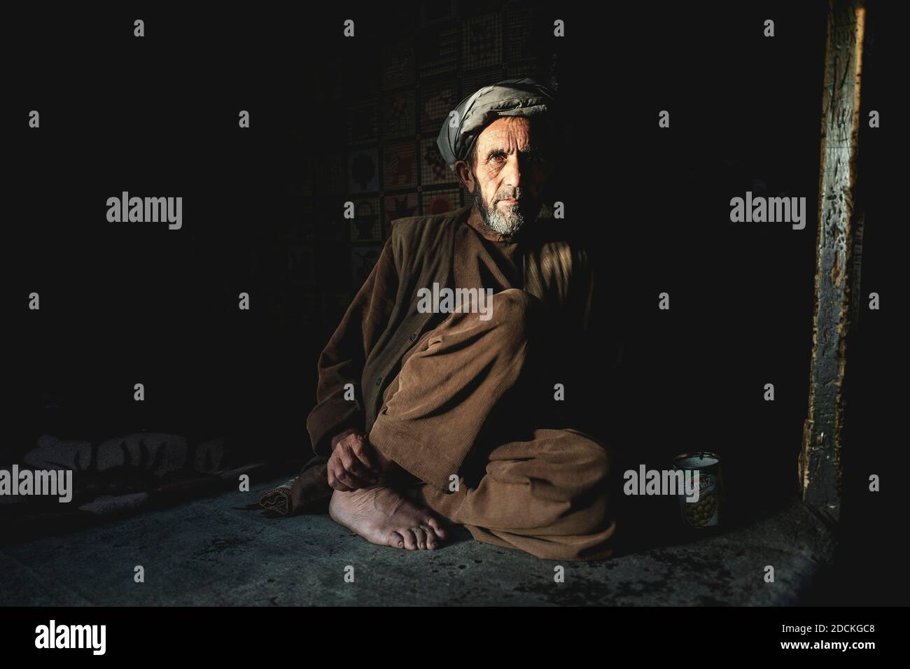 Negoziante seduto nella semoscurità sul pavimento del suo negozio, Ishkashim, Afghanistan Foto Stock