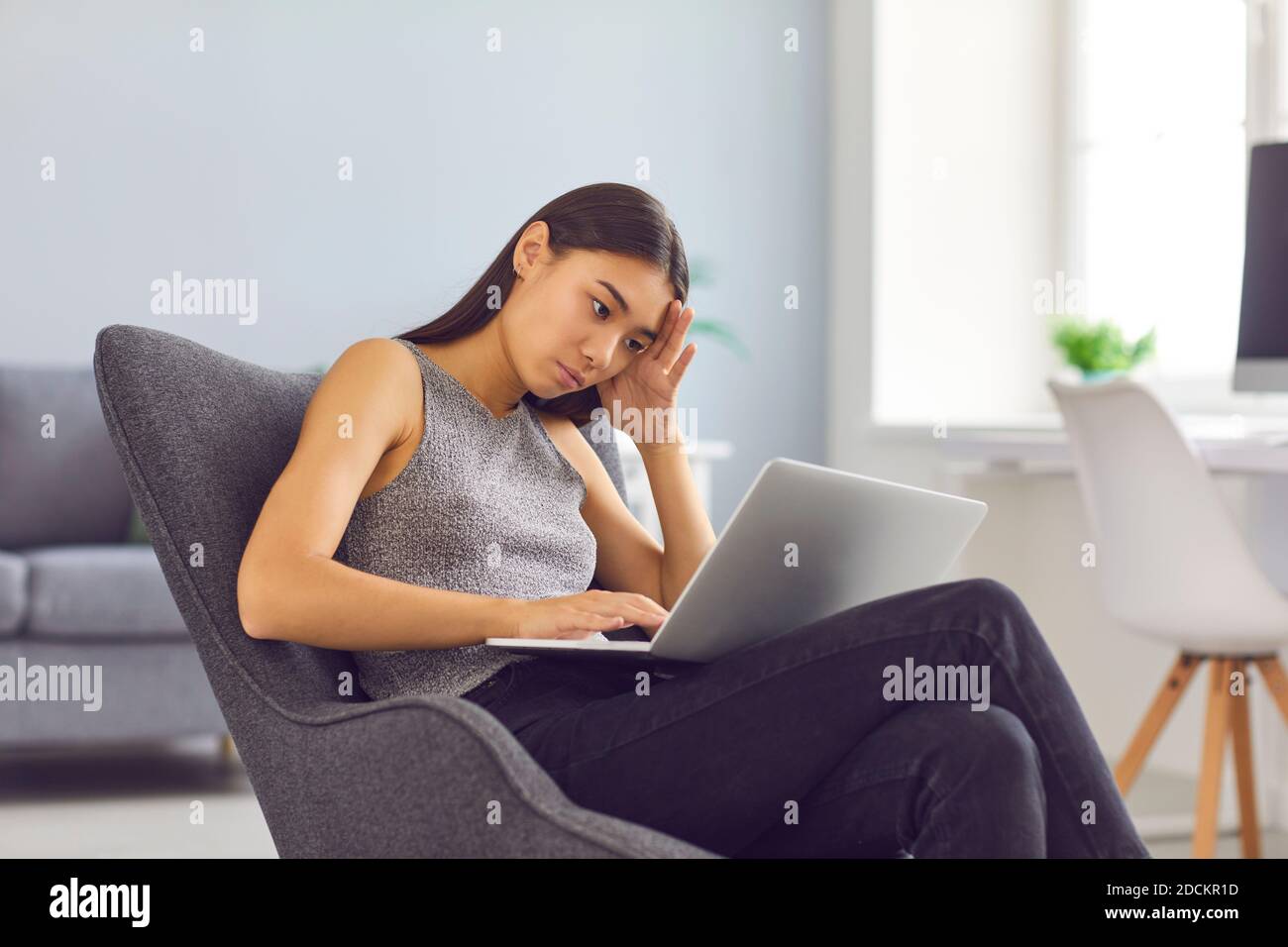Stanca, bruciata, infelice giovane donna che cerca di lavorare al suo progetto su un computer portatile Foto Stock