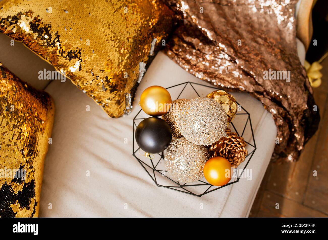 Palline con glitter oro, beige e nero per decorazioni natalizie in cesto  nero di metallo su divano chiaro con cuscini e coperta dorati. Carta  vacanza, selec Foto stock - Alamy