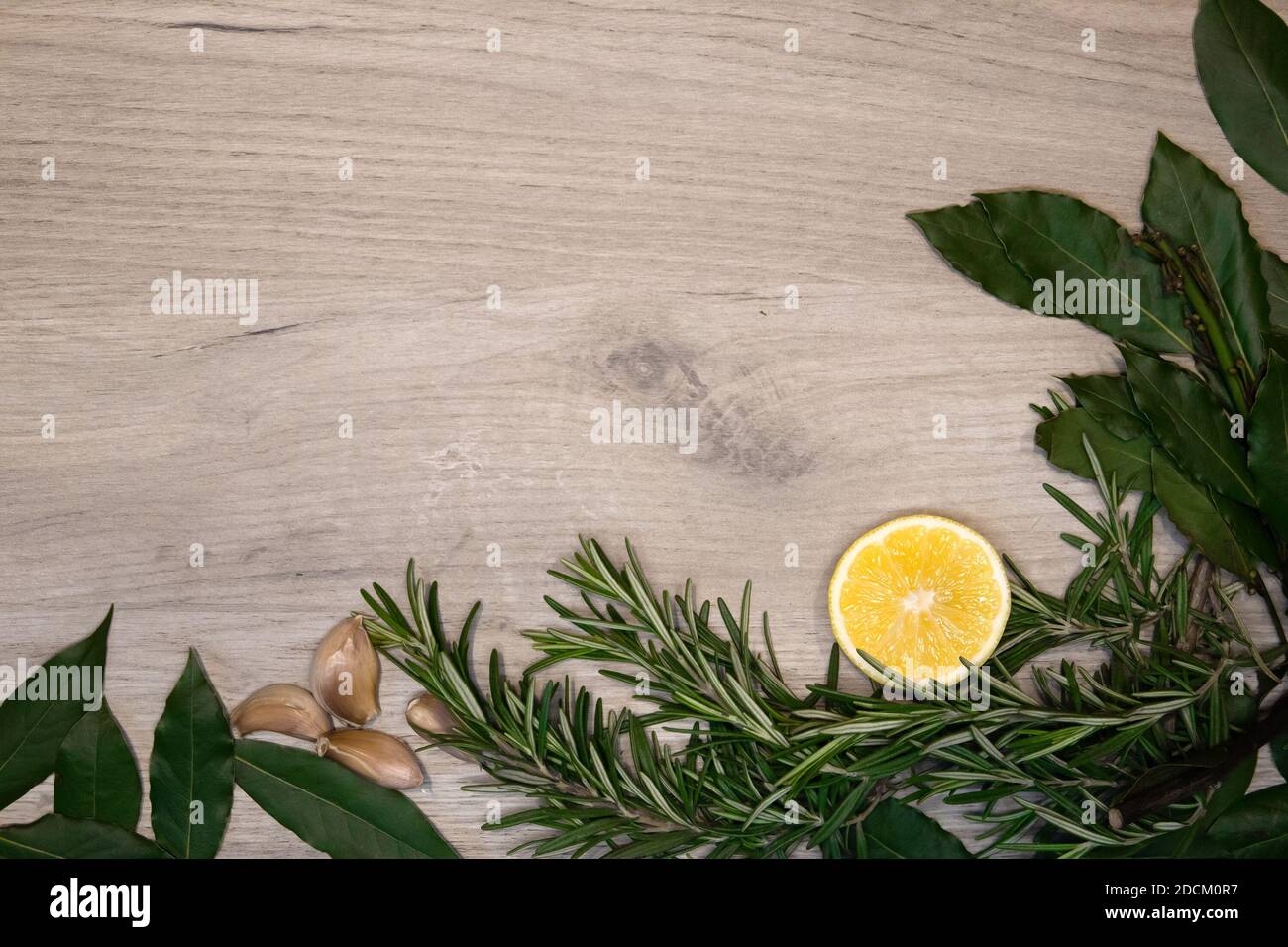 Cornice alimentare con rametti di rosmarino, foglie di alloro, mezzo limone e spicchi d'aglio, modello di design Foto Stock